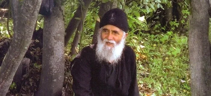 Saint Paisios sitting in forest